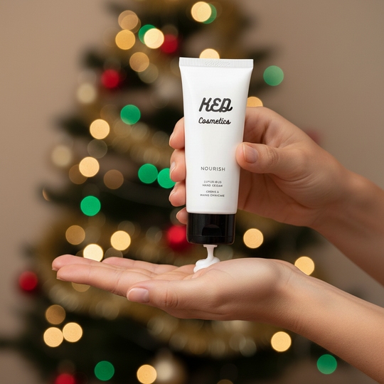 Hydrating hand cream being applied to a hand, with a festive background of colored lights and a Christmas tree.
