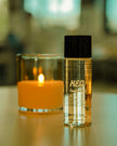 Bottle of brightening vitamin C toner next to a lit candle, showcasing hydration and radiance benefits.